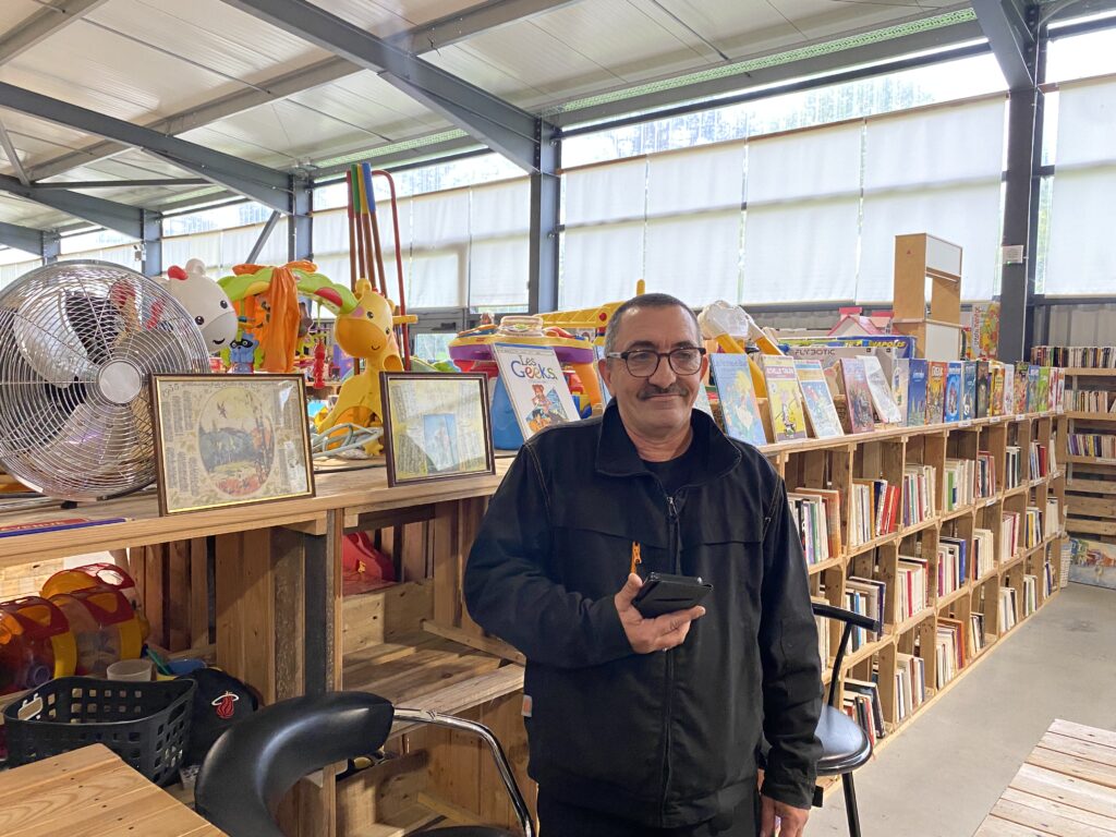 Sébastien devant son stand de livres à Emmaüs.