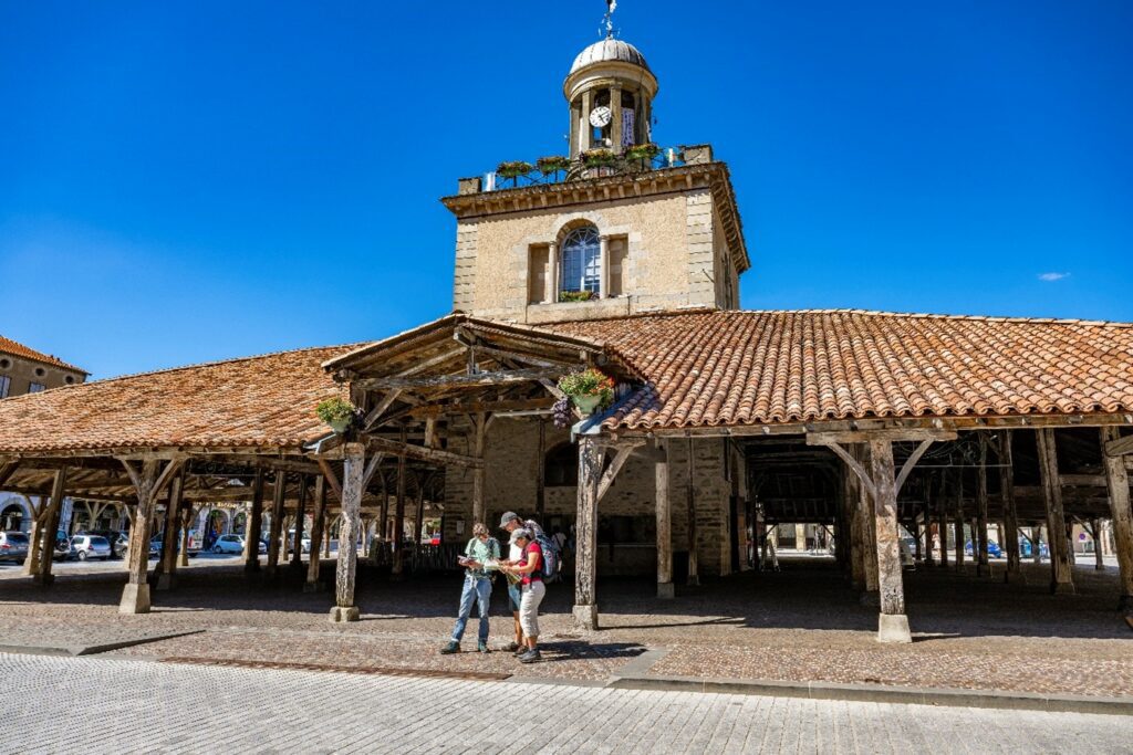 Pélerins sur la place centrale ou se dressent la Halle et son Beffroi. Un chemin passe par la ville de Revel
© Association ACSJO